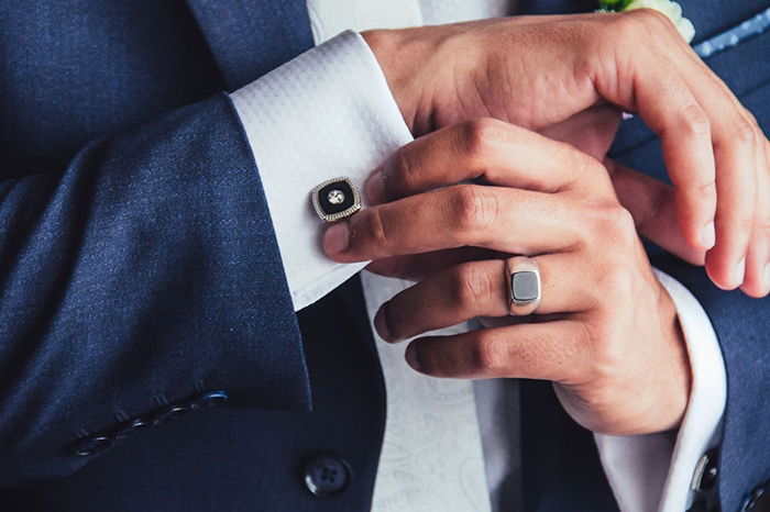 man hold the cuff of his shirt wearing a cuff link and men's ring