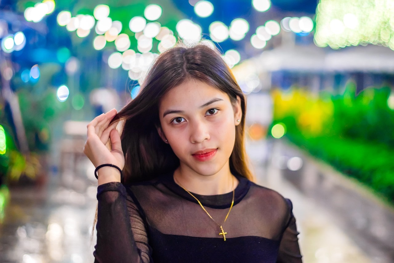 A woman walking down the street at night wears a cross necklace.