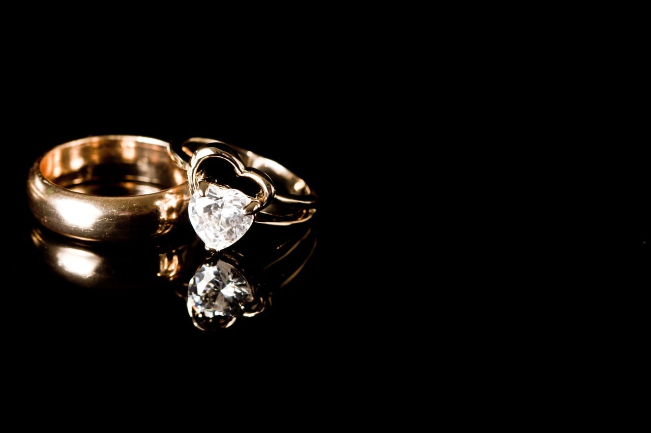 a unique engagement ring and a wedding band sitting on a black surface