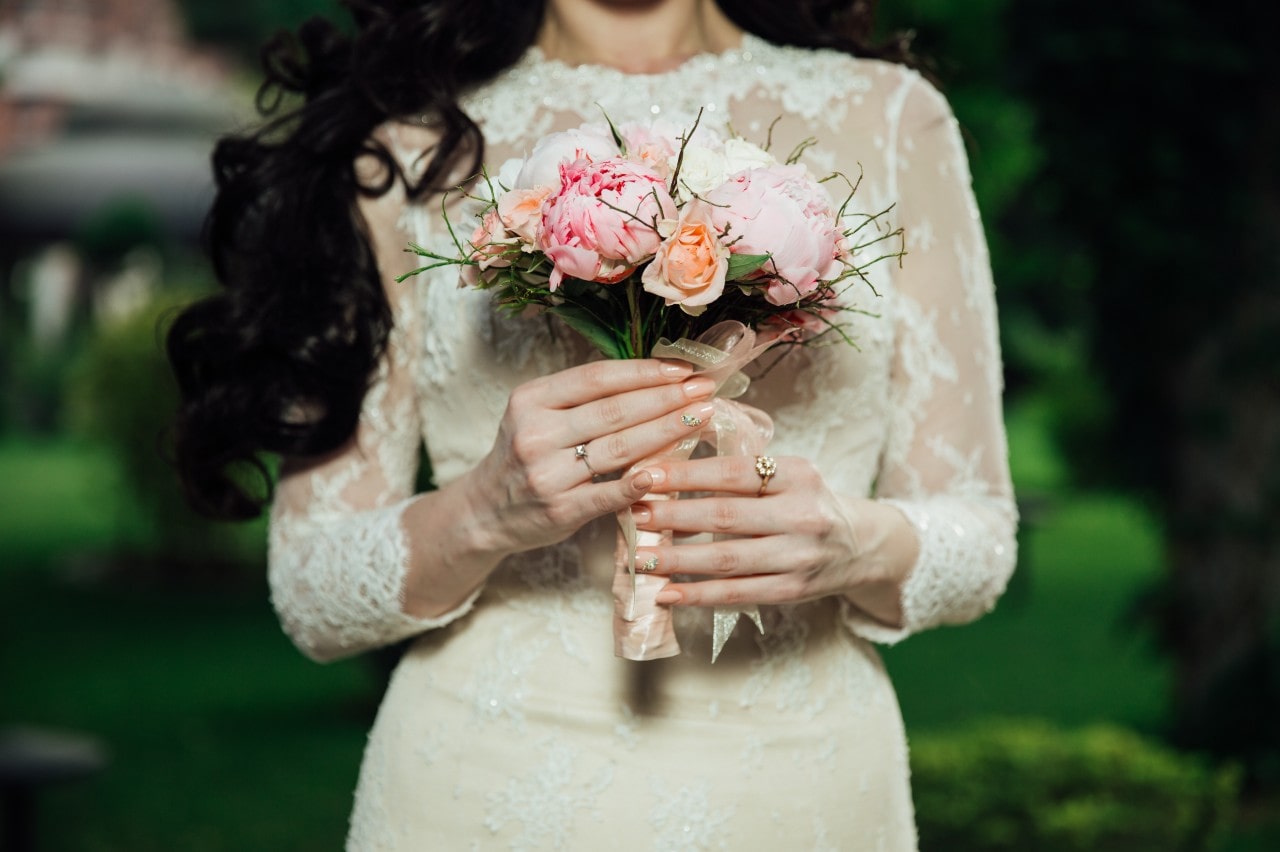 A close-up of a minimalist bride walking down the aisle, holding a small bouquet.