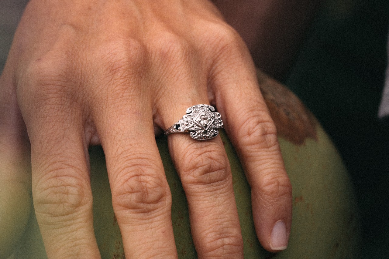 A close-up of an older woman’s hand, wearing an ornate white gold engagement ring.