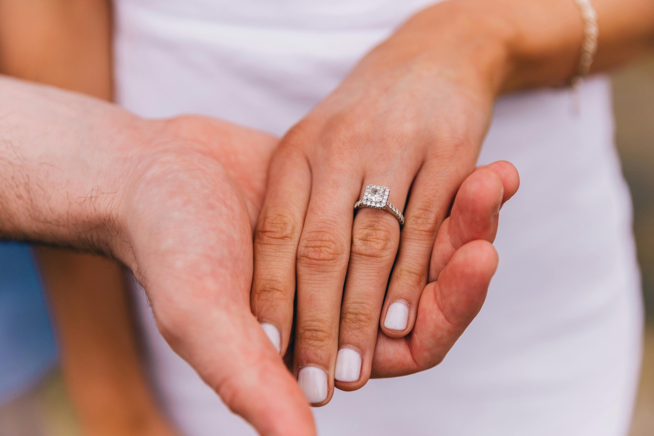 A close-up of a bride-to-be’s hand, wearing an elegant white gold engagement ring.